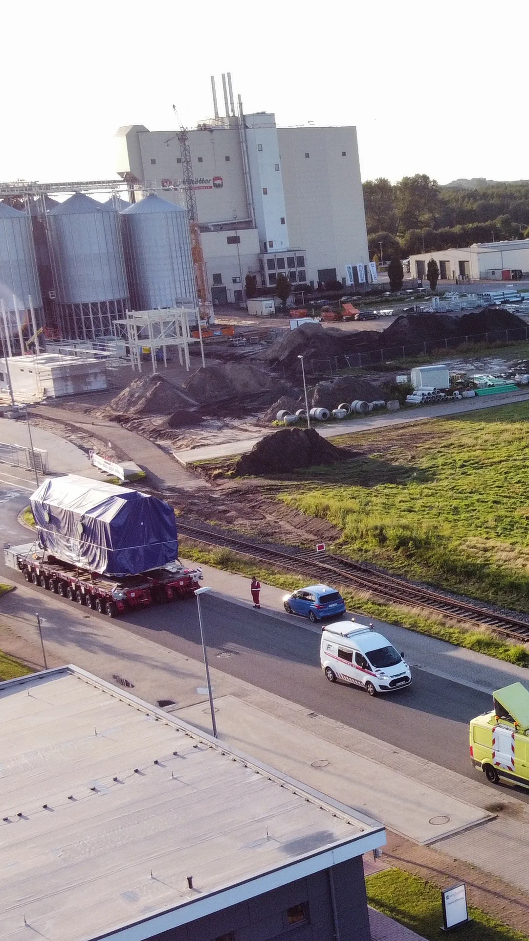 Schwertransport mit verplantem Bauteil auf dem Weg zu einer Werksanlage mit Silos