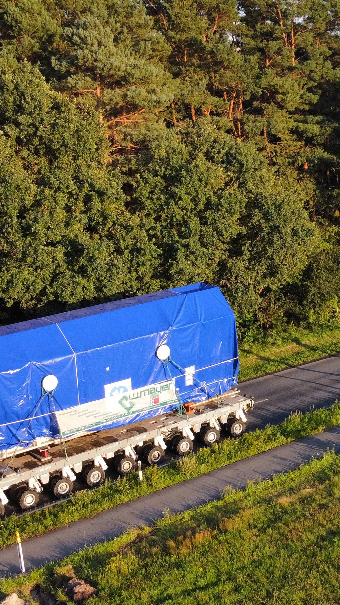 Schwertransport von W. Mayer navigiert einen Kreisverkehr im Abendlicht