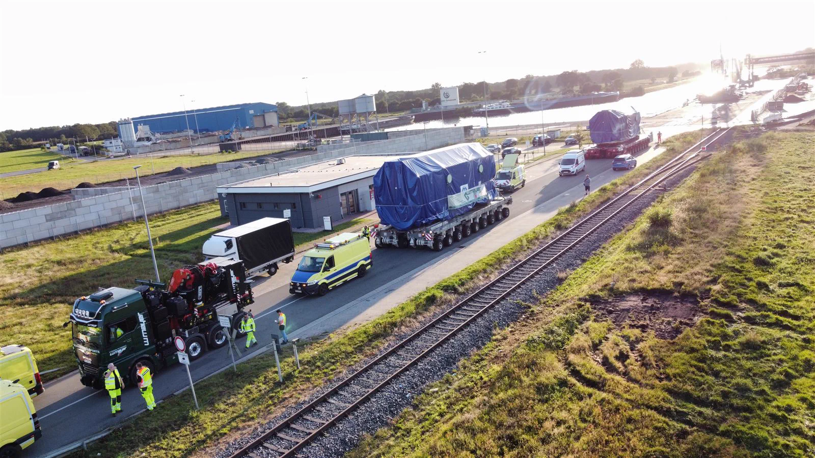 Schwertransport-Konvoi von W. Mayer mit Begleitfahrzeugen an einem Bahnübergang